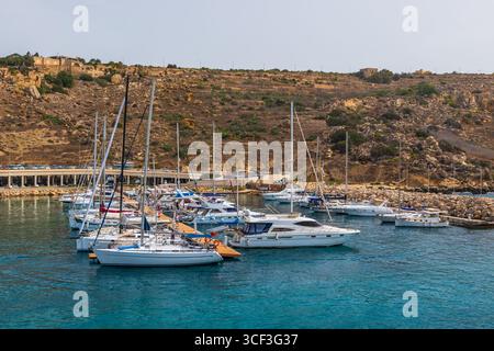Gozo, Malta - 23. Juni 2021: Hafen mit Booten und Blick auf die Kirchen auf dem Hügel von Gozo. Stockfoto