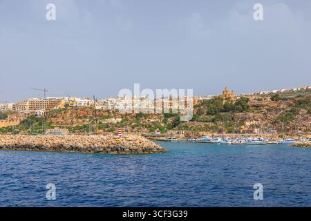 Gozo, Malta - 23. Juni 2021: Panoramablick auf Kirchen und Stadtgebäude vom Meer aus. Stockfoto