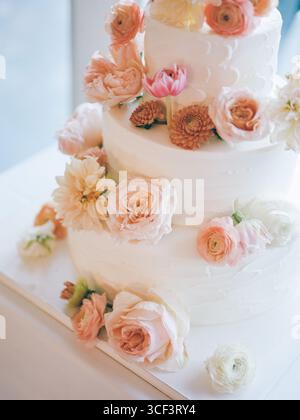 Elegante dreistöckige Hochzeitstorte mit frischen Blumen an einem Festsaal bei Tageslicht Stockfoto