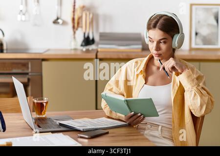 Eine schöne junge Frau entspannt sich zu Hause, beschäftigt sich mit Lesen und Notizen, während sie Tee genießt. Stockfoto