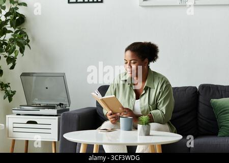 Ein entspannter Moment entfaltet sich, während eine Frau in ihrem stilvollen Wohnbereich liest. Stockfoto
