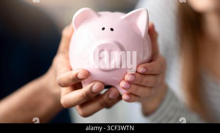 Unbekanntes Paar, Das Rosa Sparschwein In Den Händen Hält Und Geld Für Die Zukunft Spart Stockfoto
