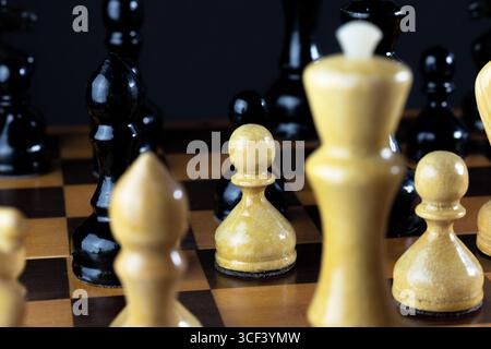 Nahaufnahme eines Schachbretts mit schwarz-weißen Stücken. Der Fokus liegt auf Bauern und einem König, die das strategische Schachspiel zeigen. Stockfoto