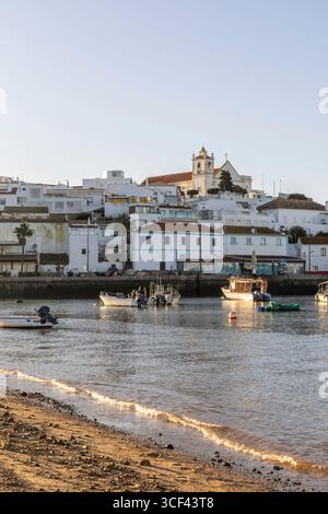 Sonnenaufgang auf dem Atlantik, Skyline eines Fischerdorfes hinter einem Hafen, Sandstrand bei Sonnenaufgang, Landschaftsaufnahmen in Ferragudo, Portimao, Algarve, Portugal Stockfoto