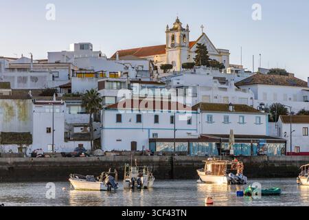 Sonnenaufgang auf dem Atlantik, Skyline eines Fischerdorfes hinter einem Hafen, Sandstrand bei Sonnenaufgang, Landschaftsaufnahmen in Ferragudo, Portimao, Algarve, Portugal Stockfoto