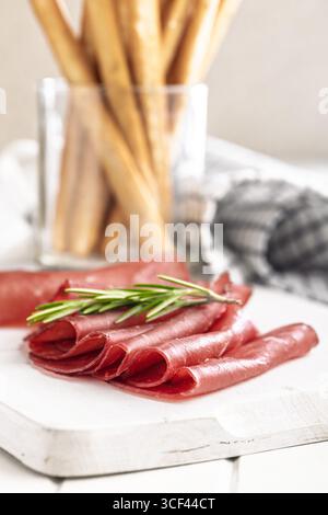 Räucherbresaola auf einem weißen Tisch. Stockfoto