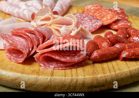 Holzbrett mit verschiedenen Wurstsorten: salamis, Schinken und Würstchen nach Stil. Texturen und Farben heben sich in einer Präsentation hervor, die ideal für ist Stockfoto