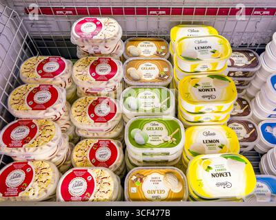 Italien - 20. August 2025: Eis verschiedener Geschmacksrichtungen in Kunststoffschalen in einer Kühltheke zum Verkauf in einem italienischen Supermarkt Stockfoto