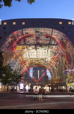 Rotterdams Wahrzeichen Markthal, erbaut 2014, entworfen von MVRDV's Winy Maas, mit 228 Apartments über einer Markthalle, die abends beleuchtet werden. Stockfoto