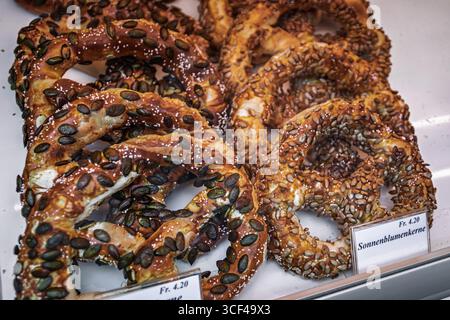 Frisch gebackene Brezeln mit Kürbiskernen und Sonnenblumenkernen zum Verkauf in einer Bäckerei, einem traditionellen europäischen Snack in Zürich, Schweiz Stockfoto