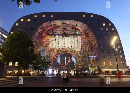 Rotterdams Wahrzeichen Markthal, erbaut 2014, entworfen von MVRDV's Winy Maas, mit 228 Apartments über einer Markthalle, die abends beleuchtet werden. Stockfoto
