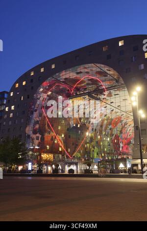 Rotterdams Wahrzeichen Markthal, erbaut 2014, entworfen von MVRDV's Winy Maas, mit 228 Apartments über einer Markthalle, die abends beleuchtet werden. Stockfoto