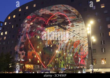 Rotterdams Wahrzeichen Markthal, erbaut 2014, entworfen von MVRDV's Winy Maas, mit 228 Apartments über einer Markthalle, die abends beleuchtet werden. Stockfoto