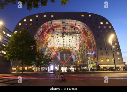 Rotterdams Wahrzeichen Markthal, erbaut 2014, entworfen von MVRDV's Winy Maas, mit 228 Apartments über einer Markthalle, die abends beleuchtet werden. Stockfoto