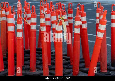 Große Anzahl von leuchtend orangefarbenen Verkehrsmeldern oder Verkehrskegeln am Straßenrand Stockfoto
