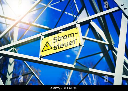 Hochspannungspylon mit Schild und Aufschrift Stromsteuer, Fotomontage Stockfoto