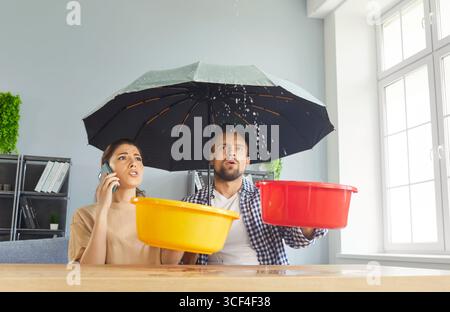 Junge, gestresste Paare, die zu Hause wegen Dachundichtigkeiten anrufen Stockfoto
