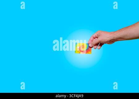 Männliche Hand, die bunte Krawattenfarbe Kreditkarten-Chip-blauer Hintergrund mit Kopierraum hält Stockfoto