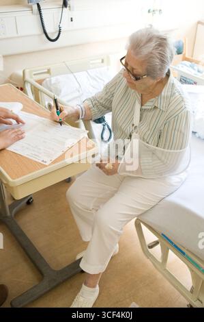 Ältere Frau Patient sitzt am Krankenhausbett Unterzeichnung Krankenhaus Entlassungspapiere Stockfoto