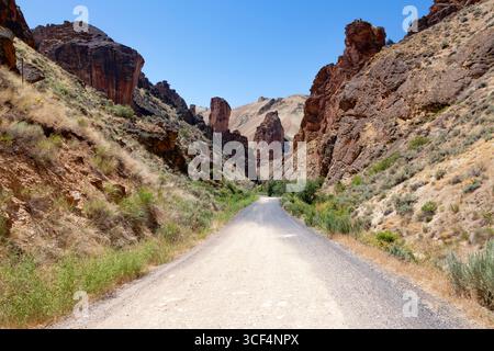 Die Leslie Gulch Road schlängelt sich durch die Basalttürme, die sich aus dem Calderaboden des Leslie Gulch Area erheben, das für die Umwelt von kritischer Bedeutung ist Stockfoto