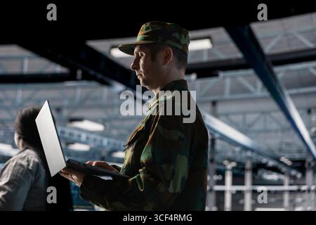 Experte für Informationstechnologie der Armee in Rechenzentren, die verschlüsselte Server zum Schutz vertraulicher Verteidigungsdaten konfigurieren. Soldat im Serverraum der Kommandozentrale, der die militärische IT-Infrastruktur verwaltet Stockfoto