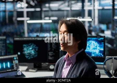 Programmierer im Rechenzentrum optimiert die Infrastruktur für KI-Aufgaben und erhöht so die Workloads. Asiatischer Mitarbeiter im Serverraum automatisiert die Systemdiagnose mithilfe von Deep Learning-Prognosen Stockfoto