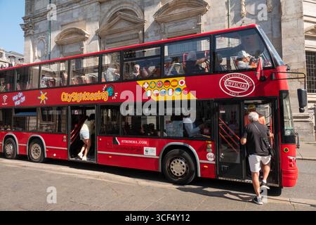 Leute, die bei sonnigem Wetter einen Doppeldeckerbus mit offenem Oberdeck sehen. Kopenhagen, Dänemark - 19. August 2025. Stockfoto