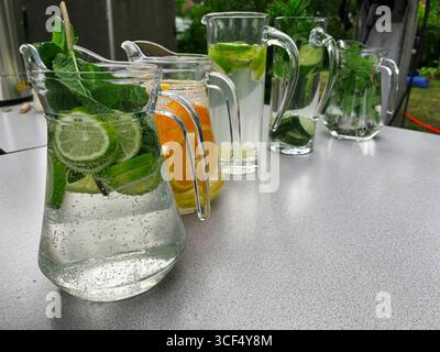Fruchtige Erfrischungsgetränke stehen in einer Reihe auf einem Gartentisch. Stockfoto