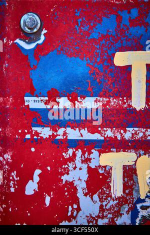 Abblätternde Lackstruktur auf verwitterter roter und blauer Metalloberfläche mit rostigem Bolzen Stockfoto