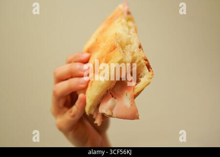 Nahaufnahme einer jungen Frau, die ein italienisches Focaccia-Sandwich mit Mortadella und Pesto-Sauce hält Stockfoto