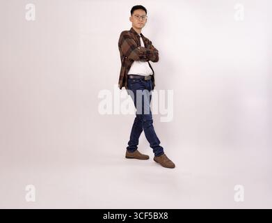 Lässiges Porträt eines jungen Mannes, der selbstbewusst in kariertem Hemd und Jeans steht Stockfoto