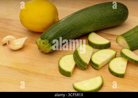 Knoblauch, Zitrone und Zucchini auf hölzernem Schneidebrett Stockfoto