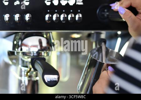 Cremona, Italien 21. Juli 2025 professioneller Barista, der mit der Wega Espressomaschine Milch aufschäumt und mit einem Krug aus Edelstahl cremigen Cappuccino zubereitet Stockfoto