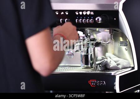 Cremona, Italien 21. Juli 2025 Barista bedient eine Wega-Kaffeemaschine und bereitet sich geschickt auf den Brühvorgang in einem belebten Café oder Restaurant vor. Stockfoto