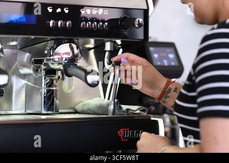 Cremona, Italien 21. Juli 2025 Barista reinigt die Dampfdüse der Wega Professional Kaffeemaschine vor der Zubereitung von Espresso und bereitet den Arbeitsplatz für die Zubereitung von c Stockfoto