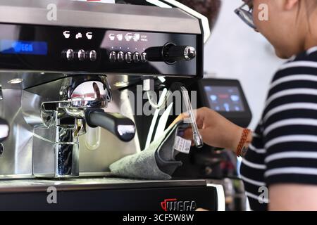 Cremona, Italien - 21. Juli 2025 Barista betreibt eine professionelle Espressomaschine, die Milch im Café aufschäumt und Heißgetränk für den Genuss der Gäste zubereitet Stockfoto