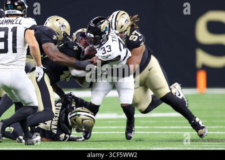 New Orleans, Usa. August 2025. Die New Orleans Saints Linebacker Danny Stutsman (47) und Defensive Tackle Khristian Boyd (97) kämpfen beide Jacksonville Jaguars, die Bhayshul Tuten (33) während eines NFL-Vorsaisonspiels am Sonntag, den 17. August 2025 in Metairie, Louisiana. (Foto: Peter G. Forest/SIPA USA) Credit: SIPA USA/Alamy Live News Stockfoto