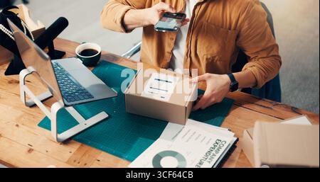 Box, Hände und Telefon mit Person im Logistikbüro zum Scannen von Barcodes oder zur Paketverfolgung. Inventar, Foto und Lieferkette mit einem Mann am Schreibtisch Stockfoto