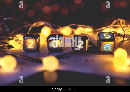 2026, Happy New Year 2026 Konzeptbanner, Flip-Kalendernummern 2025 bis 2026 auf Stahlwürfelblöcken isoliert auf Bokeh Lichter Hintergrund. Stockfoto