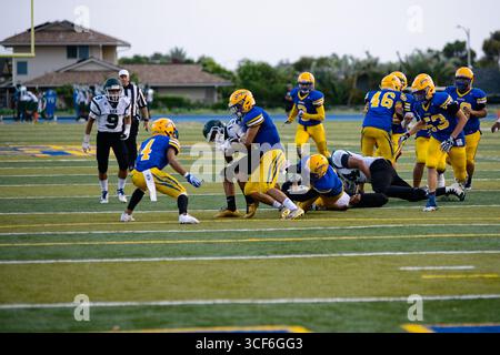 Die High School, die zurück läuft, kämpft um jeden Hof, als ein wilder Verteidiger versucht, ihn auf dem Weg in die Endzone zu stürzen. Stockfoto