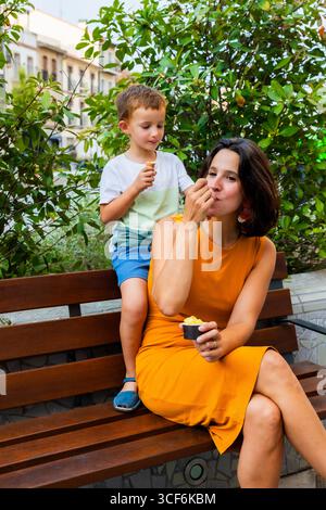 Mutter und Sohn genießen Eis auf der Parkbank Stockfoto