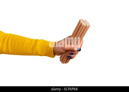 Nahaufnahme einer Hand in einer gelben Hülle, die ein Bündel umweltfreundlicher Papierhalme auf weißem Hintergrund hält. Stockfoto