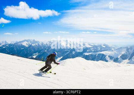 Dynamisches Bild einer Skifahrerin tragen schwarz isoliert auf der Piste Ski Downhill schnelle Bewegung in den Alpen. Aktive Winterferien, Skiabfahrten an bewölkten Tagen. Stockfoto