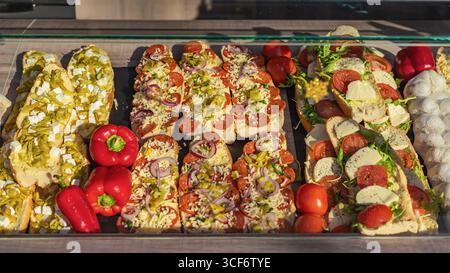 Baguette-Sandwiches zum Verkauf, Marktstand auf der Straße. Verschiedene offene Baguettes mit Käse, Peperoni, Gemüse und Feta Stockfoto