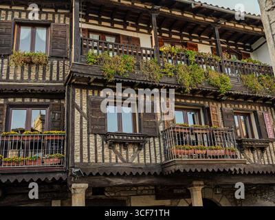 Charmantes Fachwerkgebäude mit Balkonen, die mit Blumen geschmückt sind, in einer baskischen Landstadt, die traditionelle Architektur repräsentiert Stockfoto