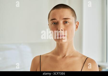 Horizontales Nahporträt einer attraktiven jungen kaukasischen Frau mit Kurzhaarschnitt, die drinnen in die Kamera blickt Stockfoto