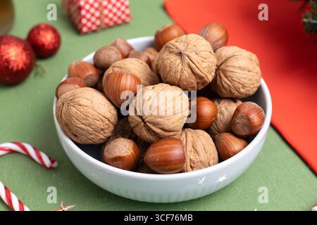Nahaufnahme einer Schüssel mit Haselnüssen und Walnüssen auf einem festlich geschmückten Weihnachtstisch Stockfoto