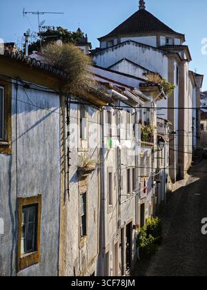 Sanftes Nachmittagslicht beleuchtet Rua de Santo Amaro, wo weiß getünchte Wände und kopfsteingepflasterte Straßen das friedliche Dorfleben widerspiegeln. Stockfoto