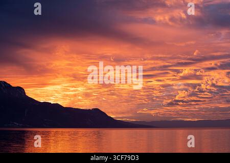 Eine Sturmfront zieht über den Lac Leman, Frankreich und den Jura. Sonnenlicht schafft es, durch Lücken im Himmel zu sickern. Sonnenuntergang, Winter 2023 Stockfoto