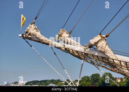 Große Bogsprits mit Rollausleger segeln vor dem Rostocker Hafen, fotografiert an einem klaren Sommertag als Teil der lokalen Charterflotte in Deutschland. Stockfoto